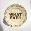 Decorative plate with floral rim and 'WHAT EVER' text on a white background