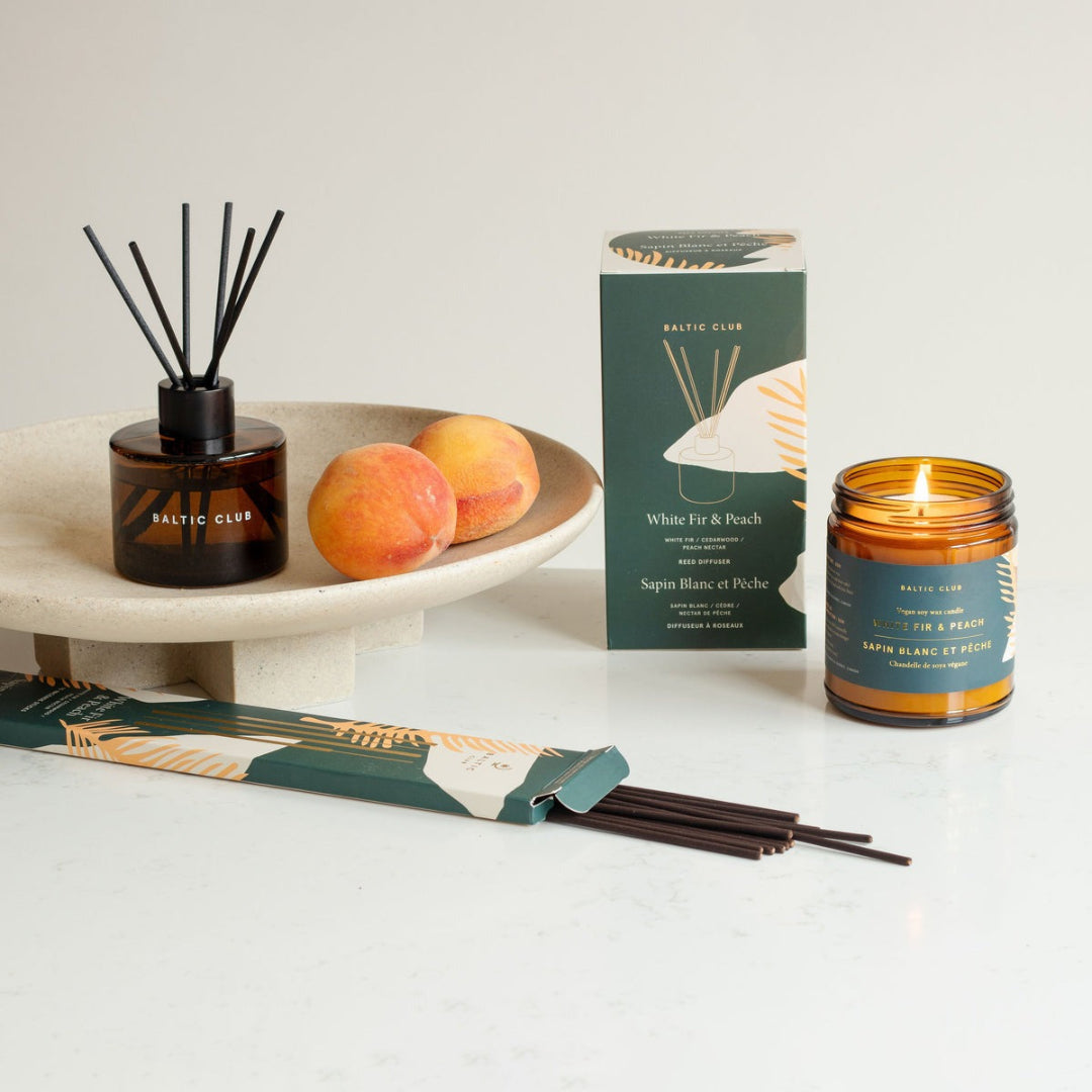 Aromatherapy diffuser, candle, and packaging on a white surface with peaches.