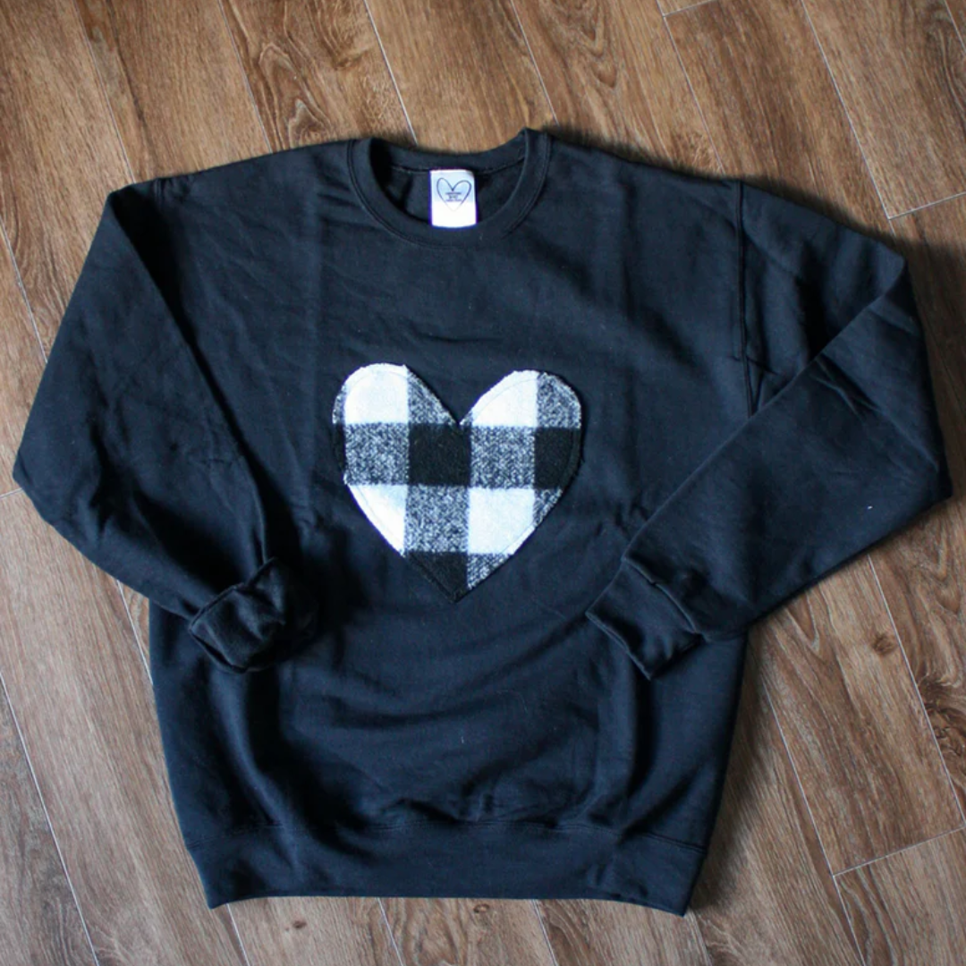 A black sweatshirt with a large, white and black buffalo plaid heart design in the center.