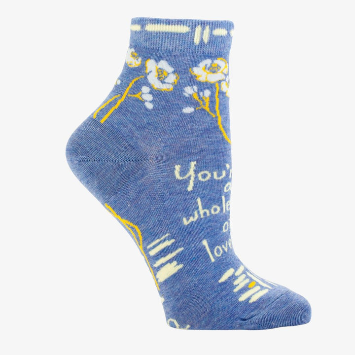 A pair of light blue ankle socks with a pattern of white and yellow flowers and branches. One sock features the text 