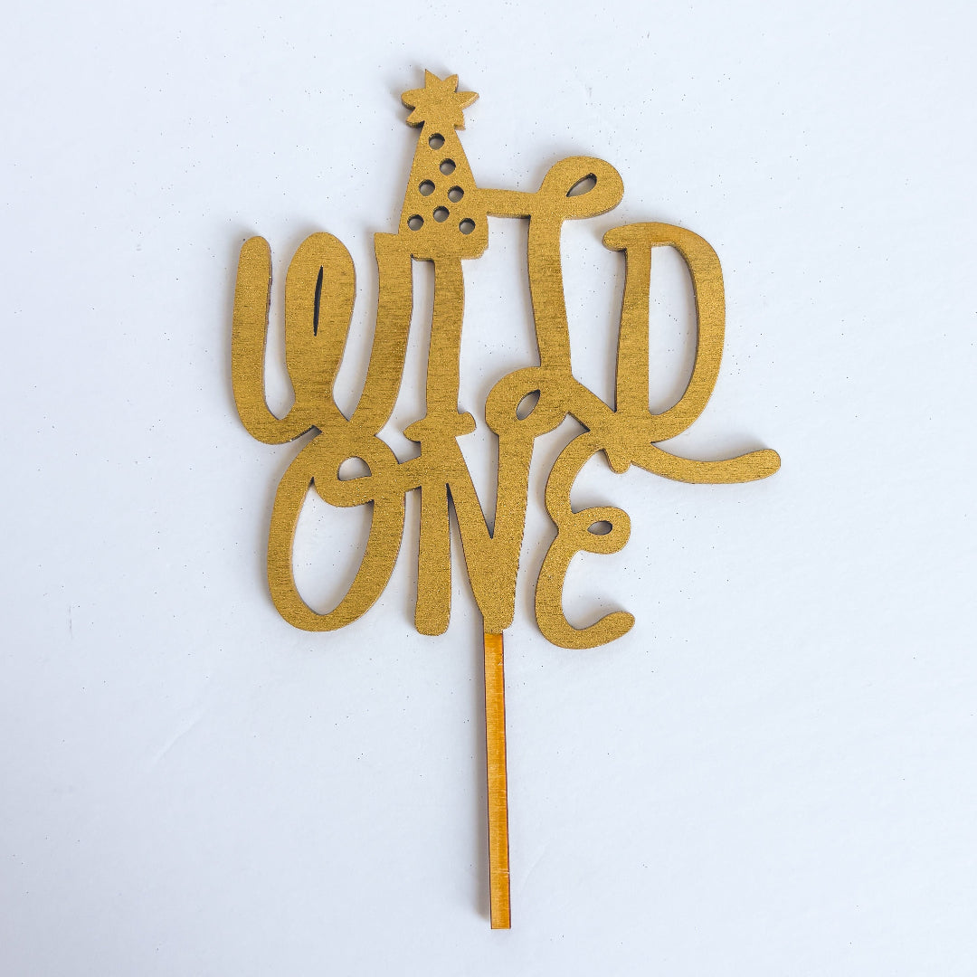 Gold 'Wild One' cake topper on a white background
