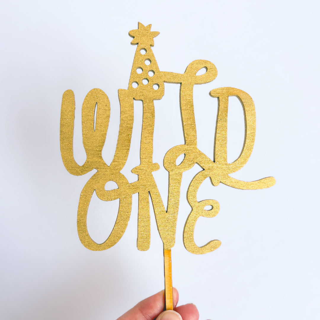 Gold 'Wild One' cake topper on a white background