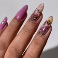 A sheet of colorful nail art stickers with various nature-themed designs. The sheet is purple and has the brand name "Deco Beauty" printed on it. There's a section titled "Wildflower" and instructions on how to apply the stickers. The stickers include designs like flowers, insects, mushrooms, and foxes.