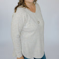 Light gray sweater worn by a person on a plain background