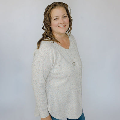 Woman wearing a light gray sweater against a plain background