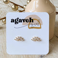Gold earrings on a 'agaveh girl' branded card with decorative elements in the background.
