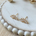 Gold earrings on a white wooden surface
