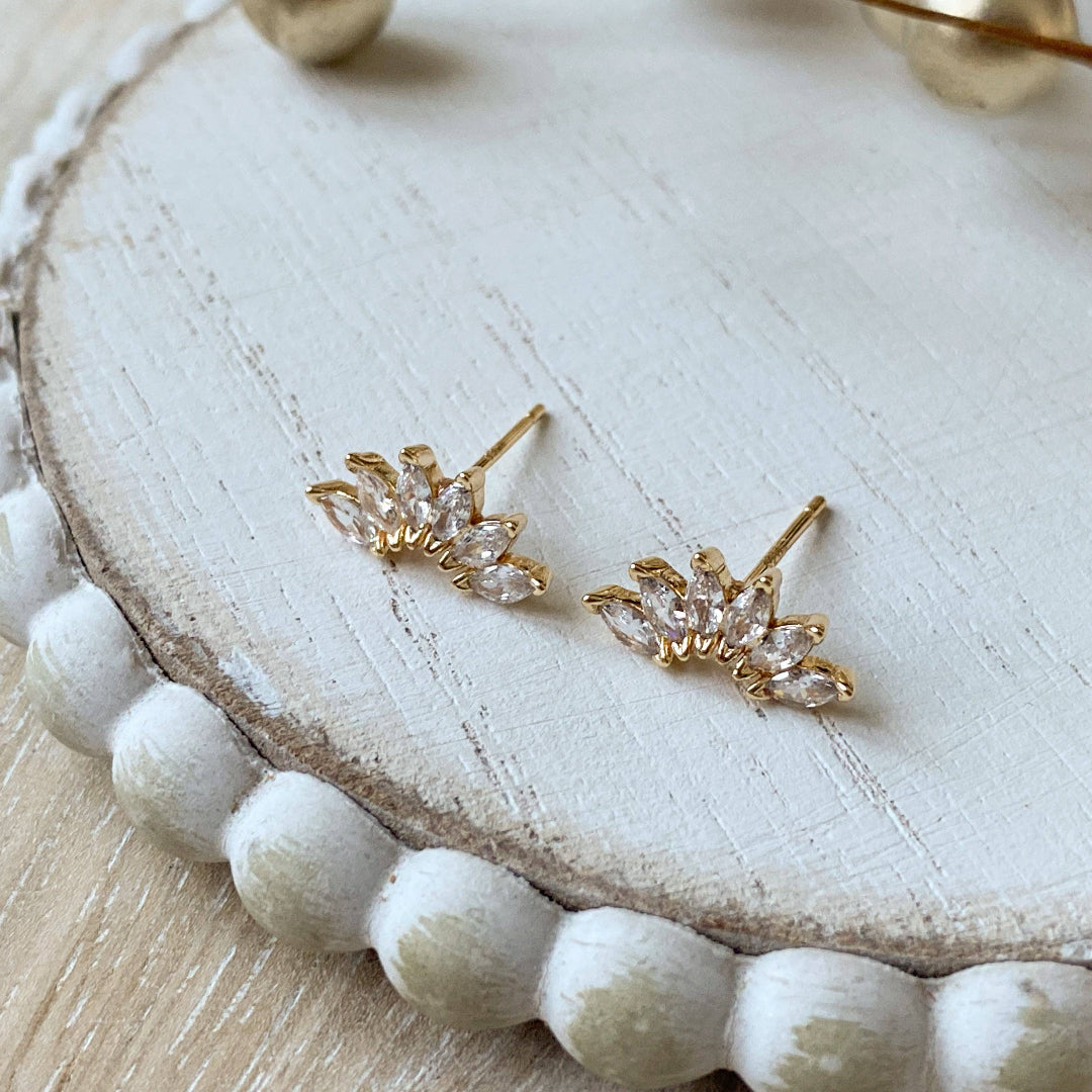 Gold earrings on a white wooden surface