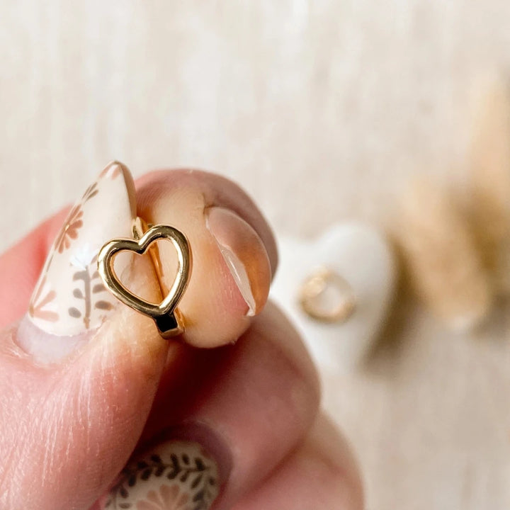 A pair of gold-plated hoop earrings shaped like hearts.