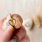 A pair of gold-plated hoop earrings shaped like hearts.