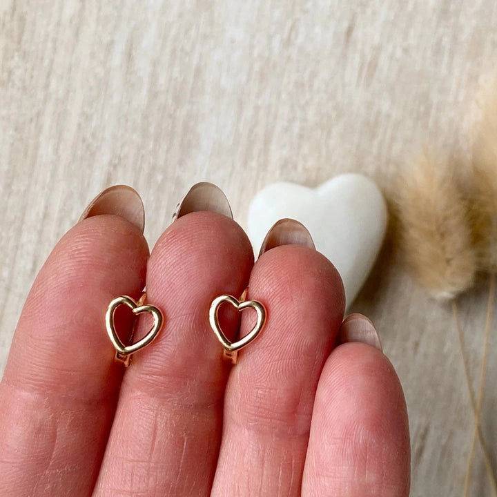 A pair of gold-plated hoop earrings shaped like hearts.