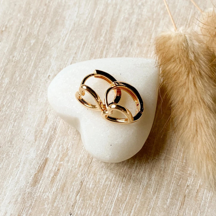 A pair of gold-plated hoop earrings shaped like hearts.