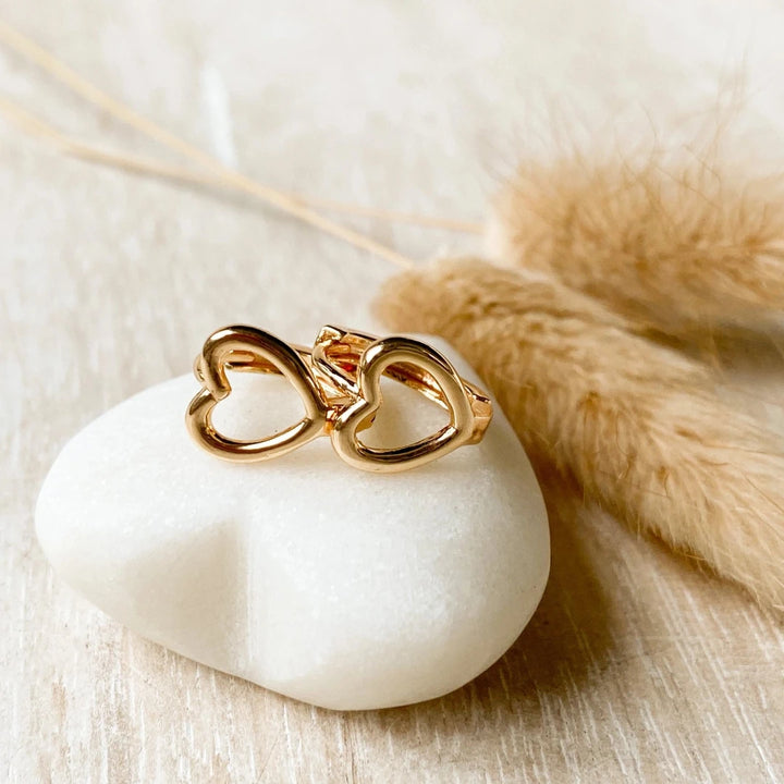 A pair of gold-plated hoop earrings shaped like hearts.