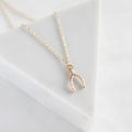Rose gold wishbone necklace on a white background