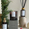 A black glass jar candle with a white label. The label reads 