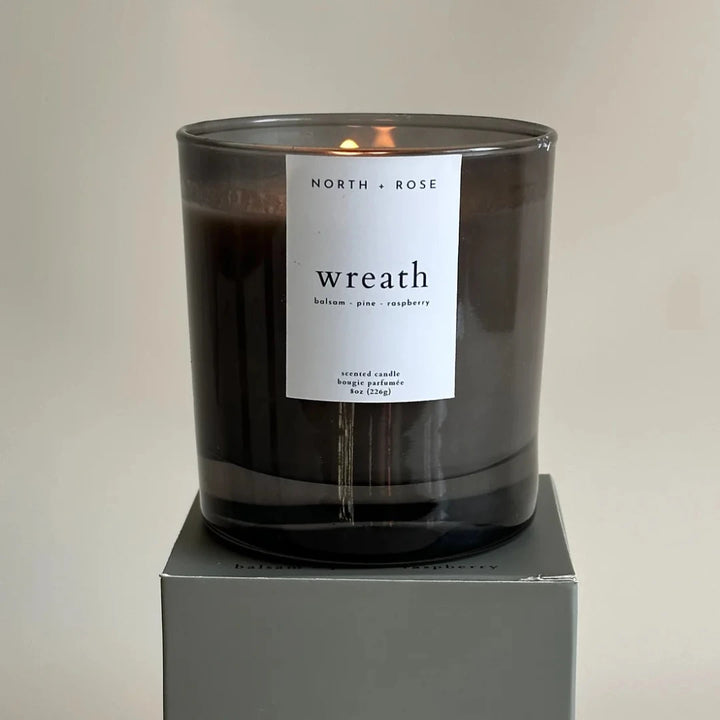 A black glass jar candle with a white label. The label reads 