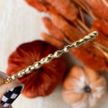 A gold-toned bangle bracelet with a row of small, rounded beads. 
