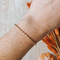A gold-toned bangle bracelet with a row of small, rounded beads. 