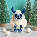 White creature with blue accents in a snowy landscape with trees