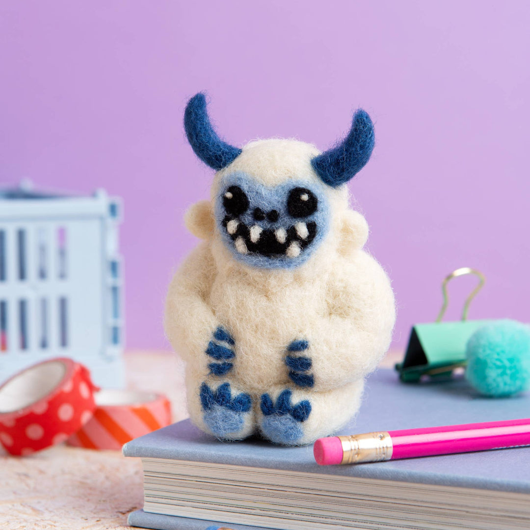 White plush toy with blue accents on a book with a purple background