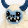 Plush toy resembling a creature with blue horns and a blue face on a white background