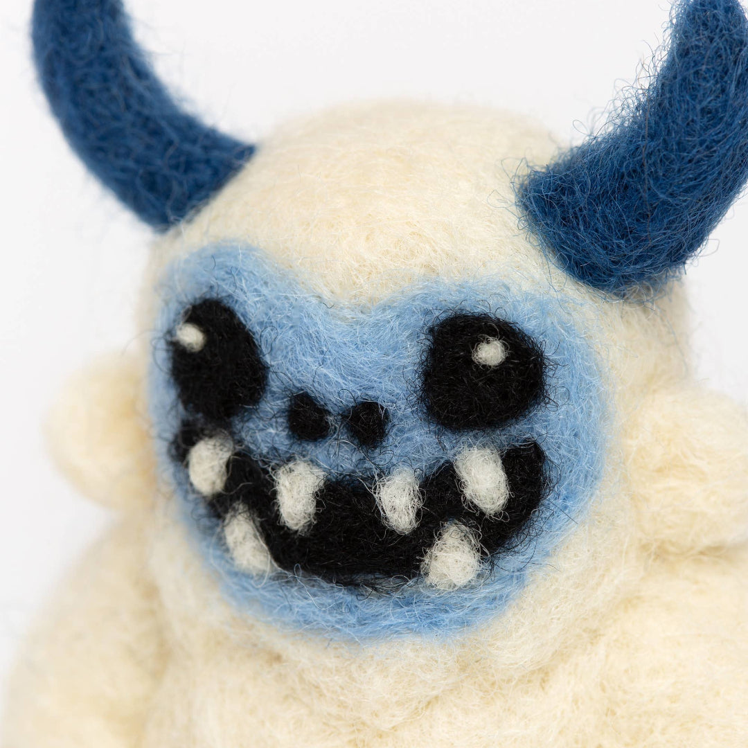 Plush toy resembling a creature with blue horns and a blue face on a white background