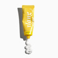 Yellow tube of cream with a white swirl on a white background