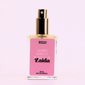 A bottle of Charleston & Harlow perfume named "Zaida." The bottle is clear glass with a gold spray cap. The label is pink with the brand name and perfume name in a bold, playful font. The fragrance notes are listed as "Amber, Apricot, Black Oud."