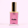 A bottle of Charleston & Harlow perfume named "Zaida." The bottle is clear glass with a gold spray cap. The label is pink with the brand name and perfume name in a bold, playful font. The fragrance notes are listed as "Amber, Apricot, Black Oud."