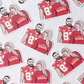A bunch of Taylor and Travis Sticker, a white sticker with an image of Travis Kelce in his football jersey and Taylor Swift in a Chiefs colours sweater that reads LOVER.