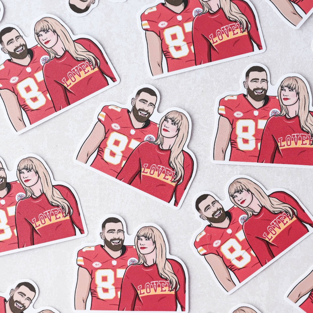 A bunch of Taylor and Travis Sticker, a white sticker with an image of Travis Kelce in his football jersey and Taylor Swift in a Chiefs colours sweater that reads LOVER.
