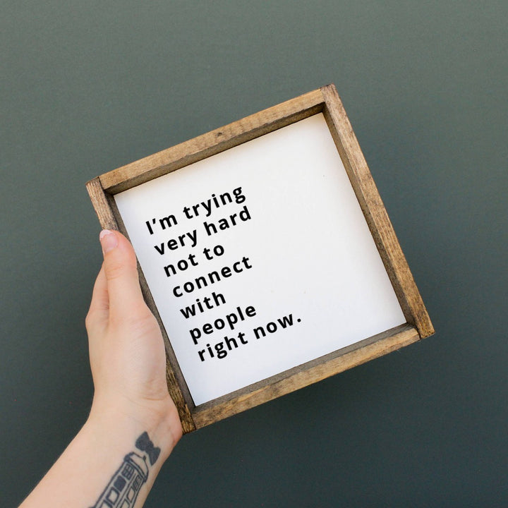 Trying Very Hard Not to Connect Wood Sign, a wood sign with a dark wood frame. It has a white background with black text reading 