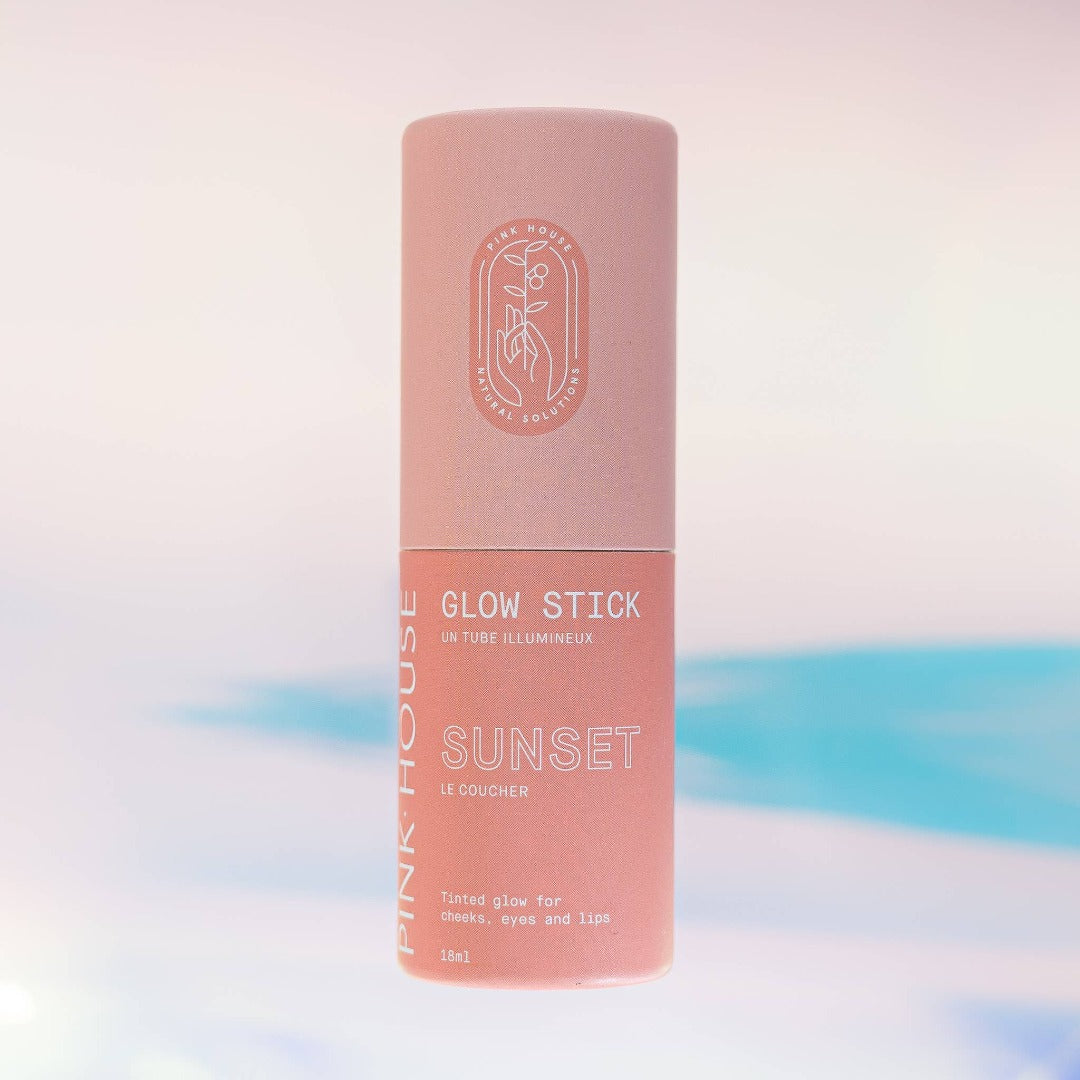 Sunset Glow Stick, a solid highlighter makeup stick in a warm coral pink sunset colour. It is presented in a cardboard tube, with a pull off top.