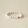 Beaded bracelet with white and rose gold beads on a beige background