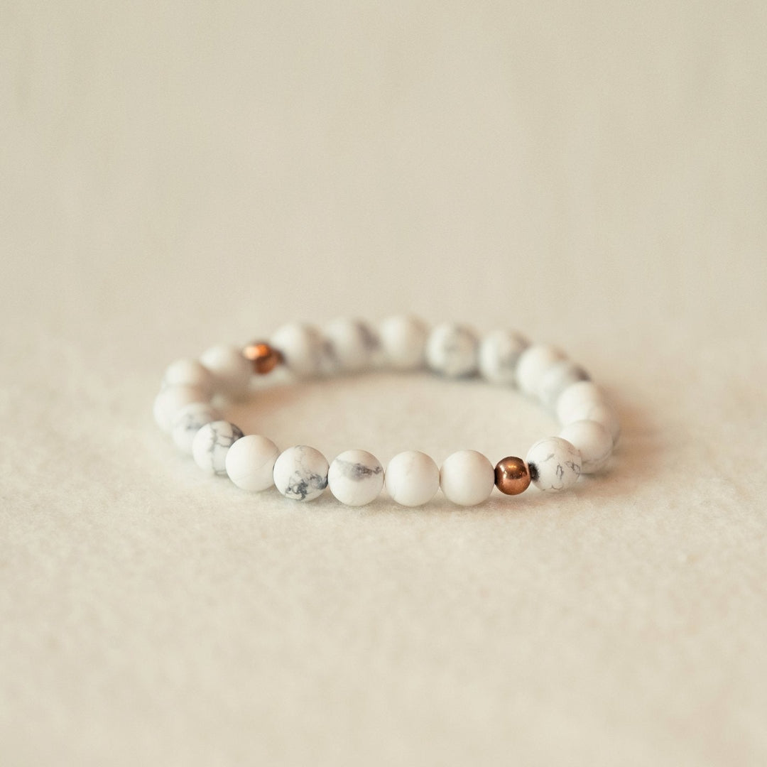 Beaded bracelet with white and rose gold beads on a beige background