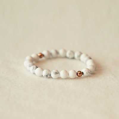 Beaded bracelet with white and rose gold beads on a beige background