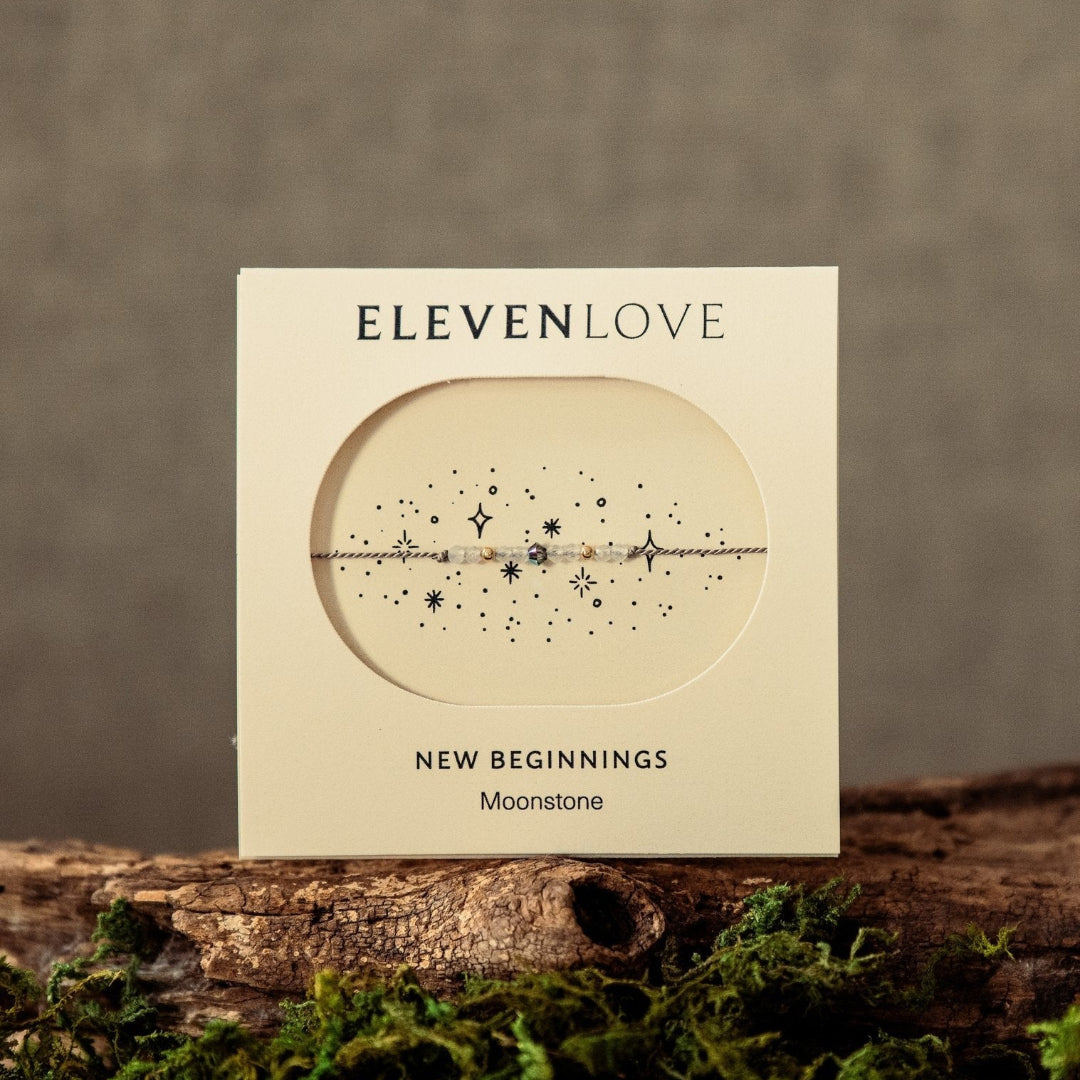 Card with 'Eleven Love' branding on a wooden surface with moss, against a brown background