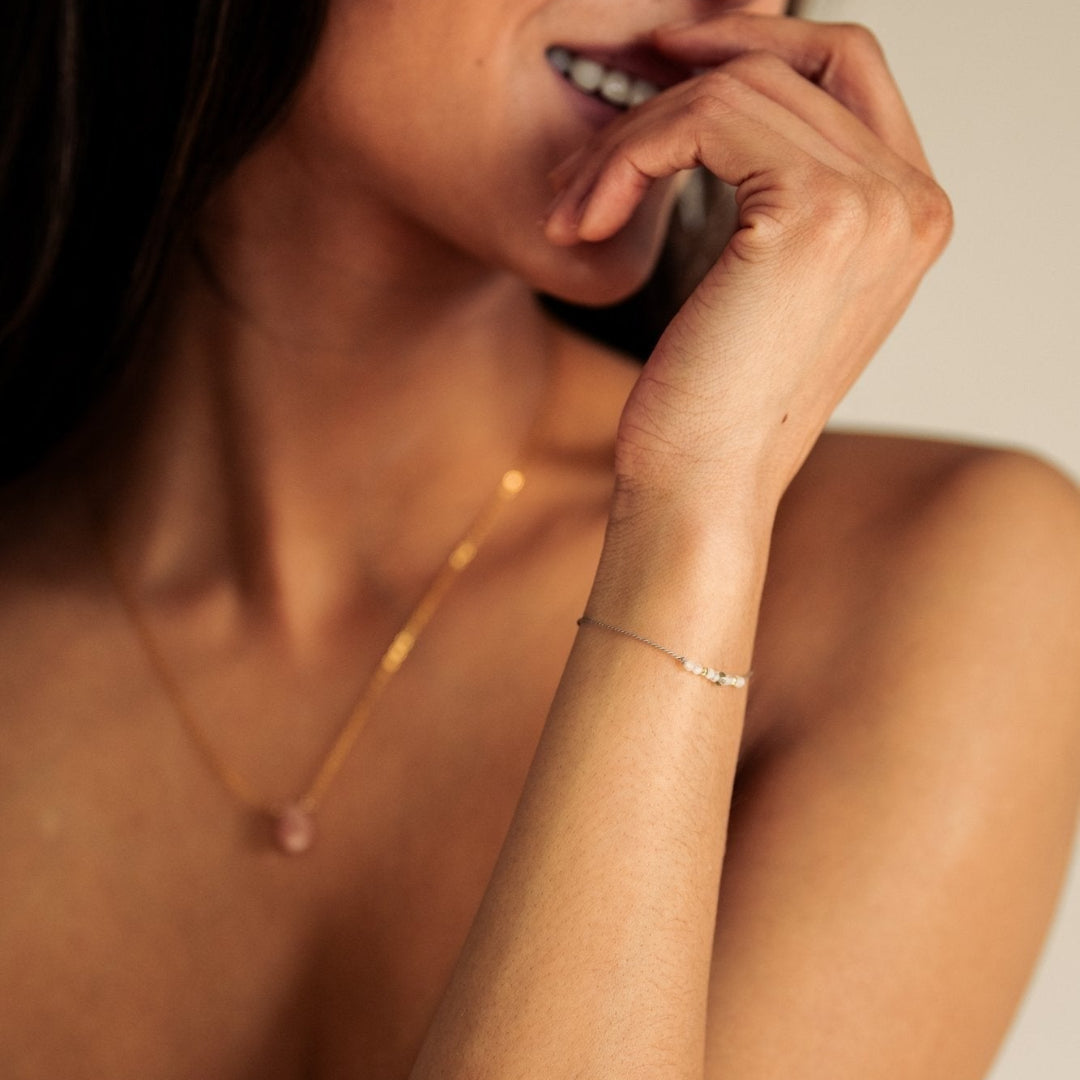 Woman wearing a necklace and bracelet with a neutral background