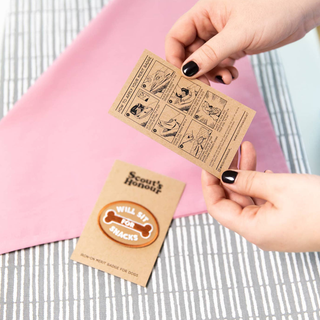 Two small cardboard cards held by a hand on a checkered fabric background