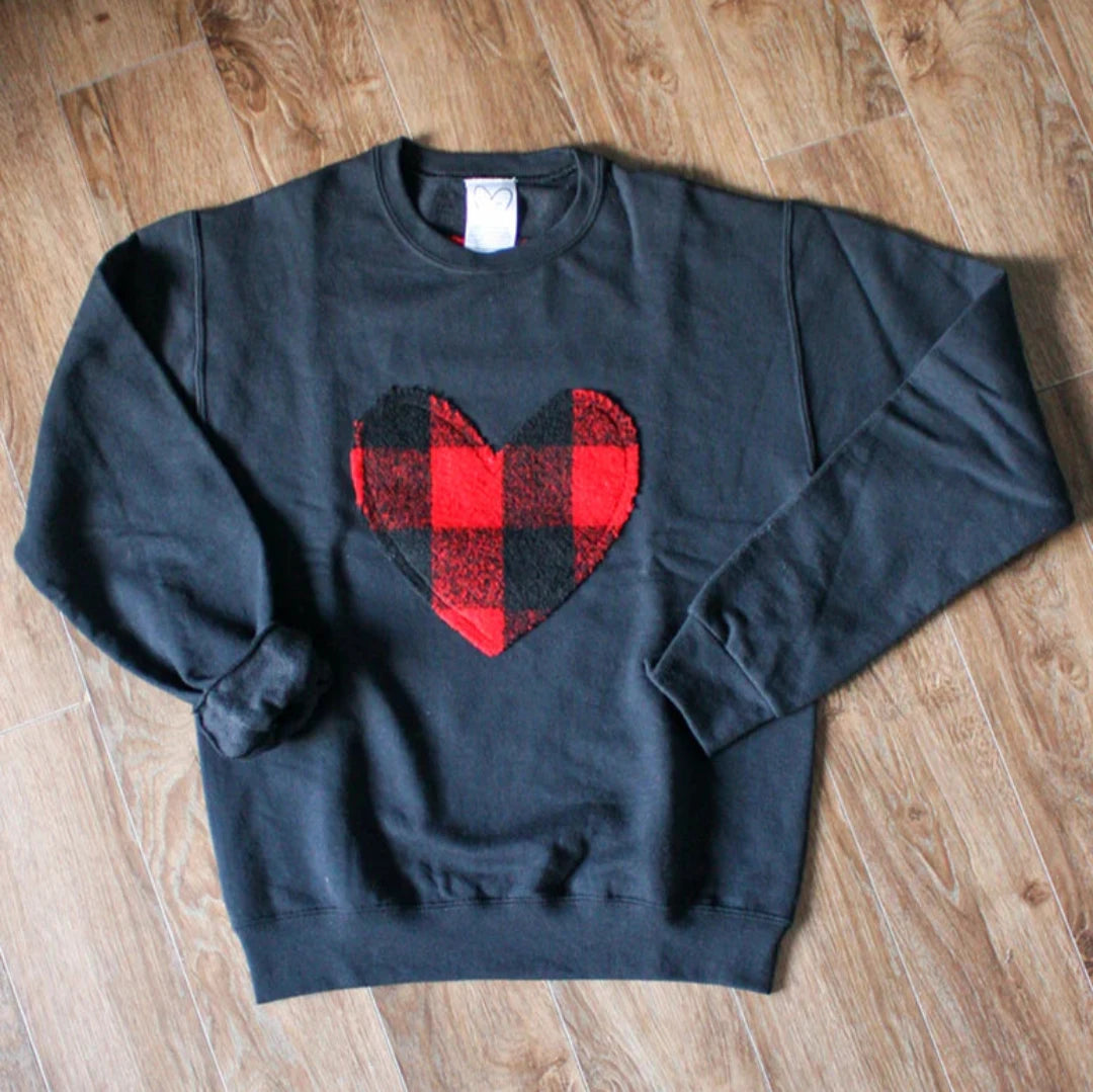 A black sweatshirt with a large, red and black buffalo plaid heart design in the center. 