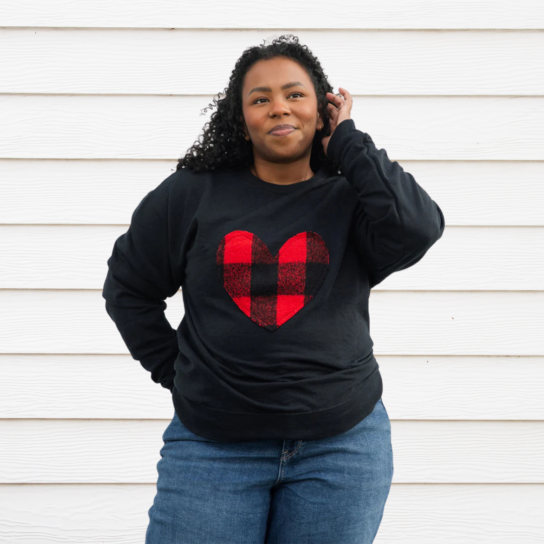 A black sweatshirt with a large, red and black buffalo plaid heart design in the center. 