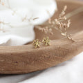 Gold snowflake earrings on a wooden surface with a soft background