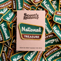 Scout's Honour 'National Treasure' iron-on merit badge for pets on a pink card, surrounded by similar patches.