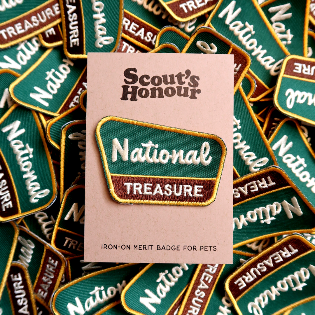 Scout's Honour 'National Treasure' iron-on merit badge for pets on a pink card, surrounded by similar patches.