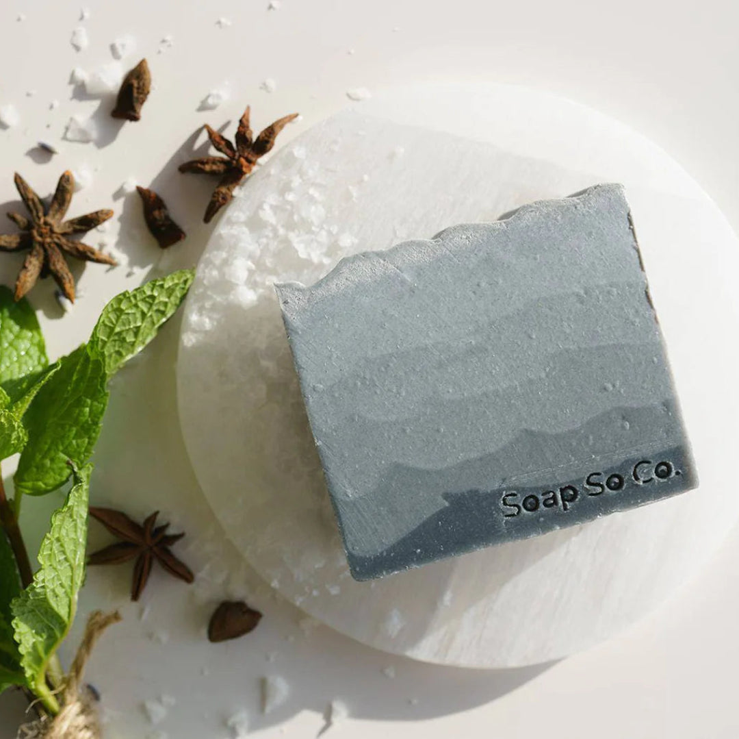 Bar of soap with 'Soap Co' branding on a white surface with herbs and spices.