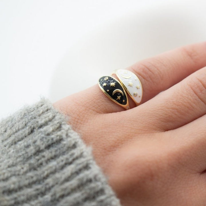 A gold ring with a black oval-shaped design featuring a crescent moon, stars, and smaller diamonds.