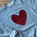 Gray sweatshirt with a red heart on a wooden surface