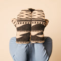 Person wearing patterned mittens on a beige background