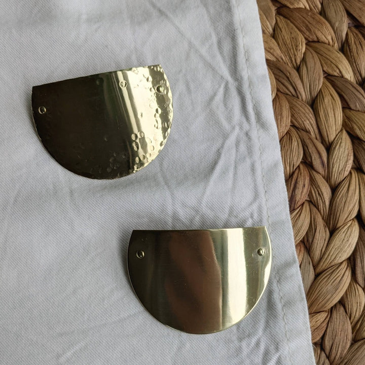 Two brass arc barrettes, one with a hammered texture and one that's smooth.