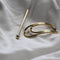 A brass hairpin in the shape of a paper clip.